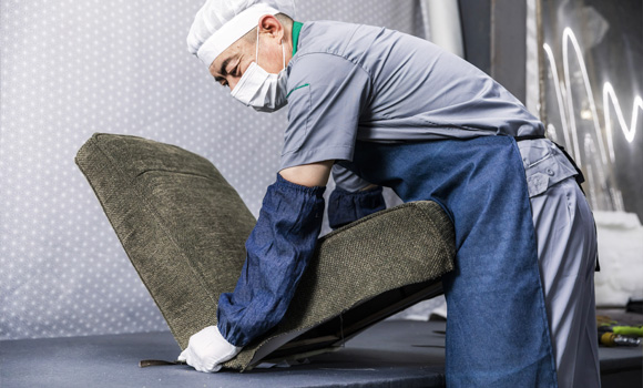 A male worker is covering the sofa with cloth