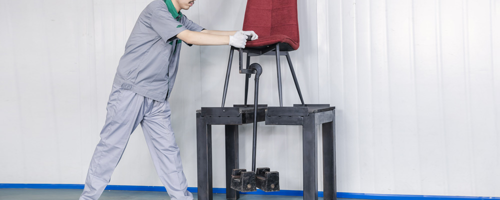 A worker is testing load-bearing capacity of a chair